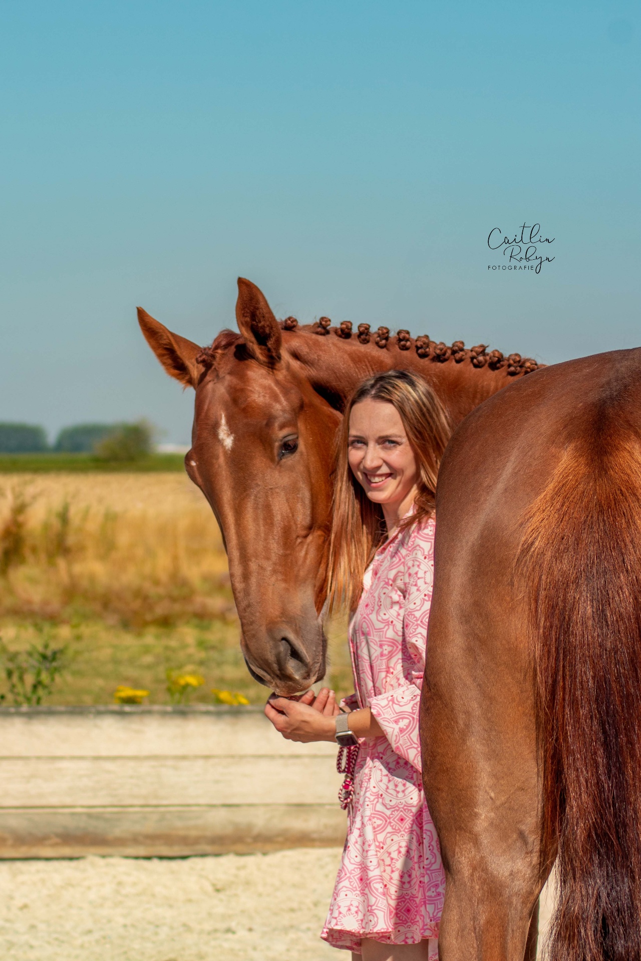 Lachende vrouw naast haar bruin paard