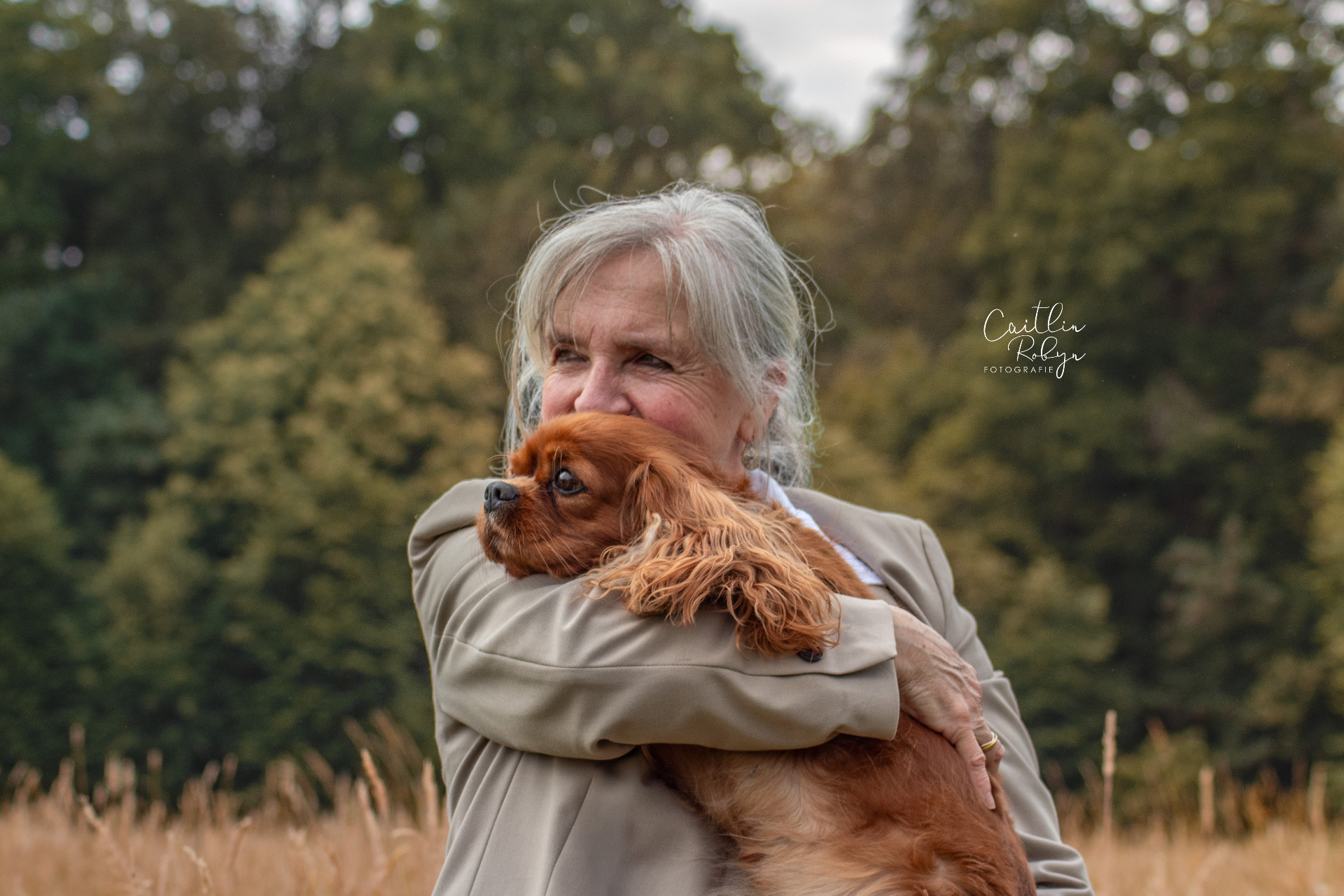 Vrouw knuffelt haar Cavalier in een veld